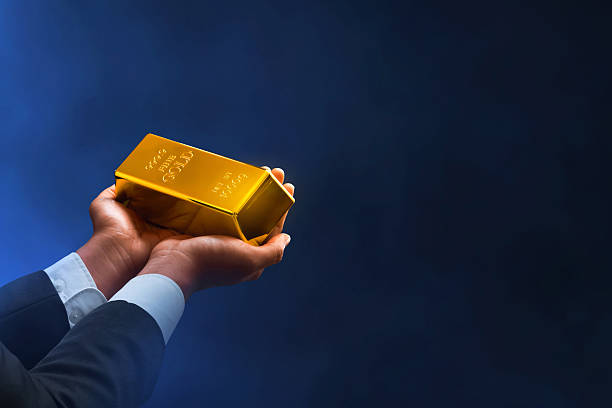 istock Businessman hand holding shiny gold bar on dark background 2255010391