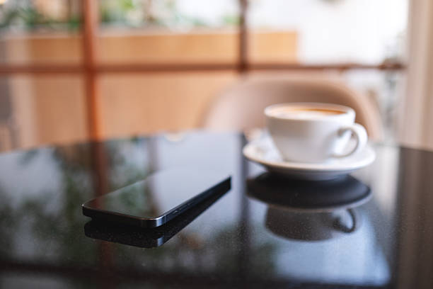 A mobile phone and a coffee cup on the table in cafe