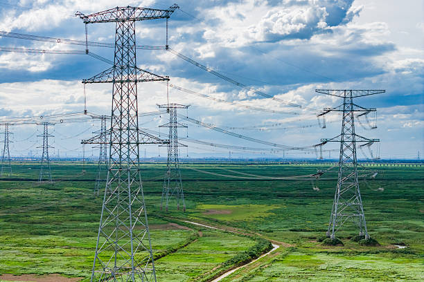 High-voltage transmission towers under blue sky and white clouds
