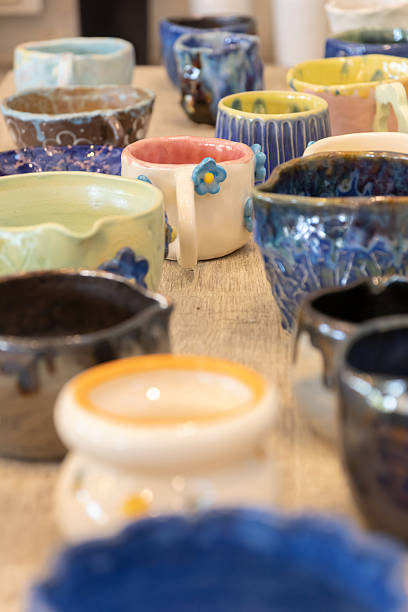 Handmade ceramic mugs and bowls with colorful glazes and floral details, cozy artisan pottery display