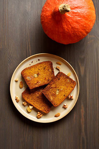 Slices of pumpkin bread with raisins and nuts on plate on brown wooden background. Top view, flat lay