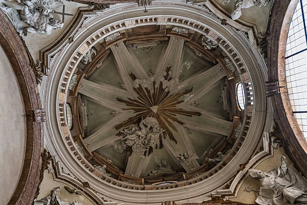 Intricately decorated vaulted ceiling with detailed frescoes and geometric patterns inside the Cattedrale dell'Immacolata Concezione in Bosa, Sardinia. Warm natural light highlights the elaborate stucco and classical motifs.