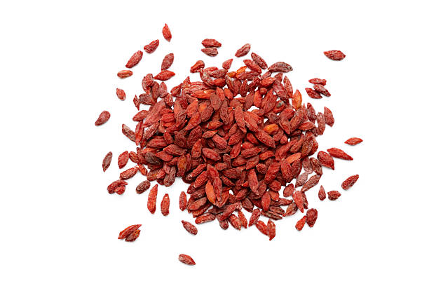 A scattered pile of dried goji berries photographed from above on a white background. The vibrant red berries with their wrinkled texture are known for their health benefits and are popular in teas, cereals, and superfood blends.