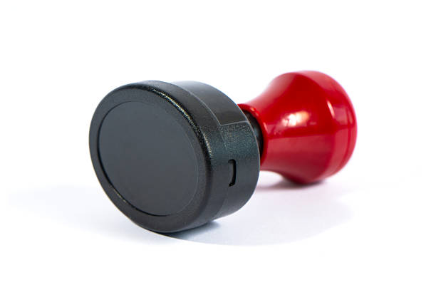 A self-inking rubber stamp with a red handle isolated on a white background. Essential office stationery used for document approval, validation, and official business