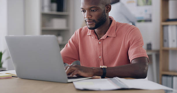 istock Black man, laptop and typing with document, article comparison or review in creative office. Journalist, reading or tech in agency for website update, topic research or paperwork for planning 2255038963