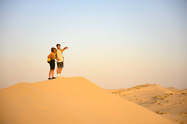 istock Couple hiking desert sand dune exploring horizon during sunset 2255039270