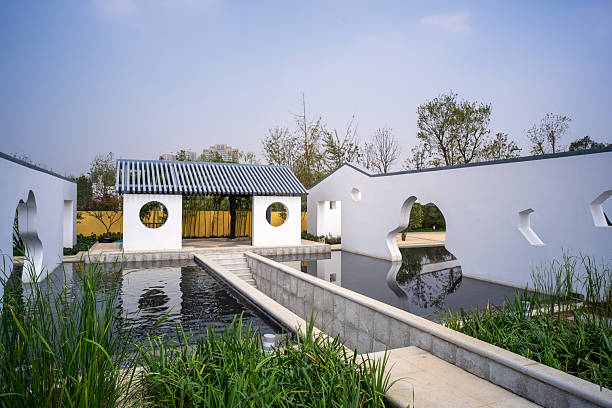 Wuhan, China - September 16, 2015: A modern Chinese style garden courtyard featuring white walls with openings and a reflection pool at Wuhan Garden Expo Park.