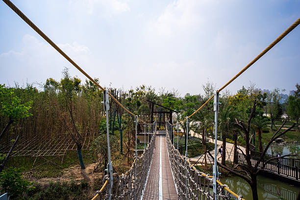Wuhan, China - September 16, 2015: Wide view of a wooden rope suspension bridge crossing over a landscape area at Wuhan Garden Expo Park.