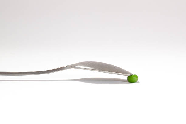 Tip of a table spoon squeezing a green pea