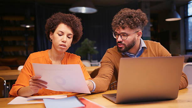 istock Businesswoman and businessman working together in modern office, analyzing documents, using laptop 2255047354