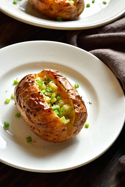 Stuffed potato with green onion on white plate. Close up view