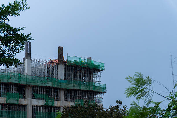 Skyward Build Construction site view with greenery against cloudy sky.