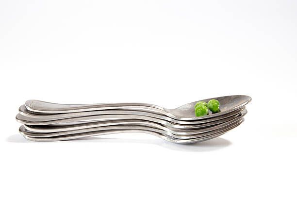 Green peas in a bowl with a wooden spoon on a white background.