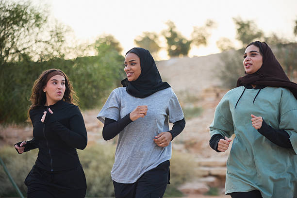 Active young women exercising in public park. Multiracial female friends are jogging with each other. They are wearing sports clothing.