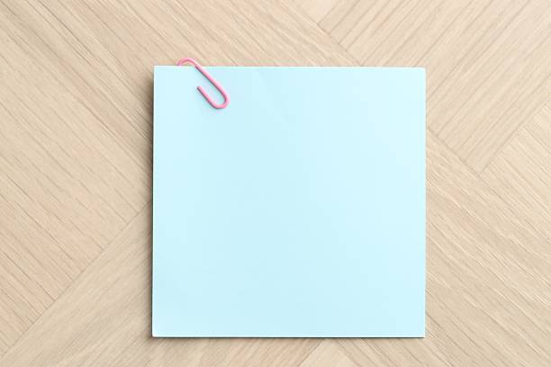 Paper note with clip on wooden table, top view. Space for text