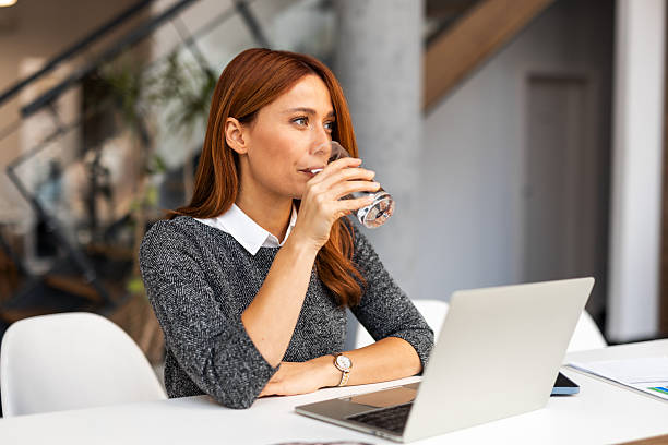 istock Businesswoman drinking water while working in modern office 2255058705
