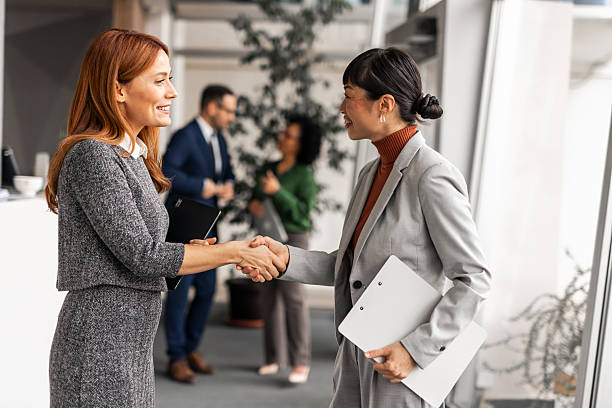 istock Businesswomen shaking hands making partnership agreement in office 2255058792
