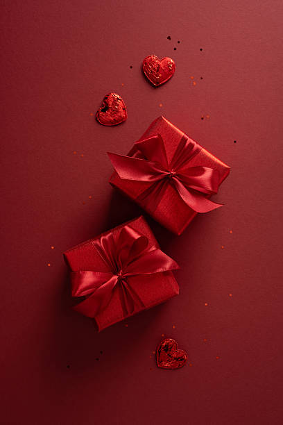 istock Two vertical red gift boxes tied with satin ribbons sit among heart chocolates on a deep red background, creating a romantic Valentine scene perfect for gifts, greeting cards, and festive promotions 2255071851