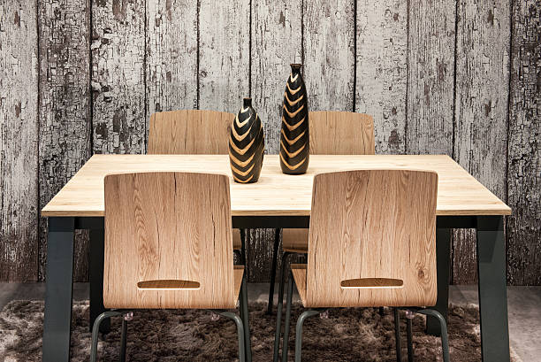 Front view of an empty wooden dinning table with four chairs shot in front of a white bricks wall