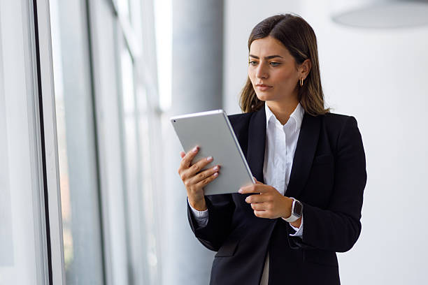 istock Businesswoman using digital tablet standing in modern office space, focused on work and technology 2255073353