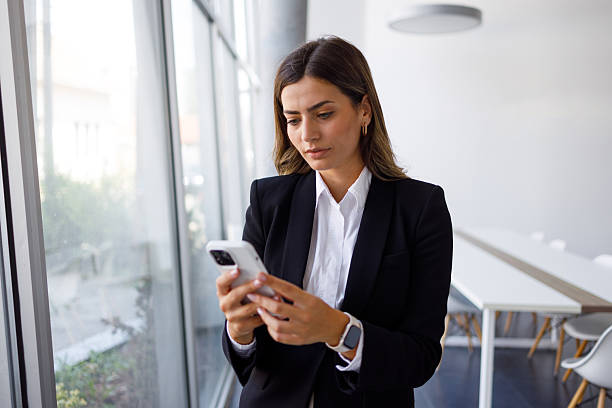 istock Businesswoman using smartphone in modern corporate office setting, staying connected and managing tasks 2255073636