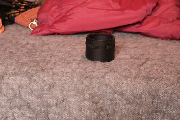 Camera lens on grey carpet with red jacket