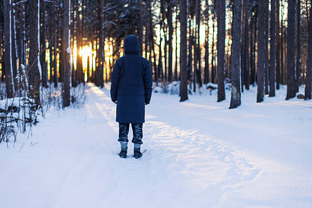 Man silhouette in winter forest. Sunset light