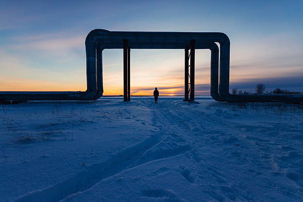 Man silhouette under pipes against winter sunset