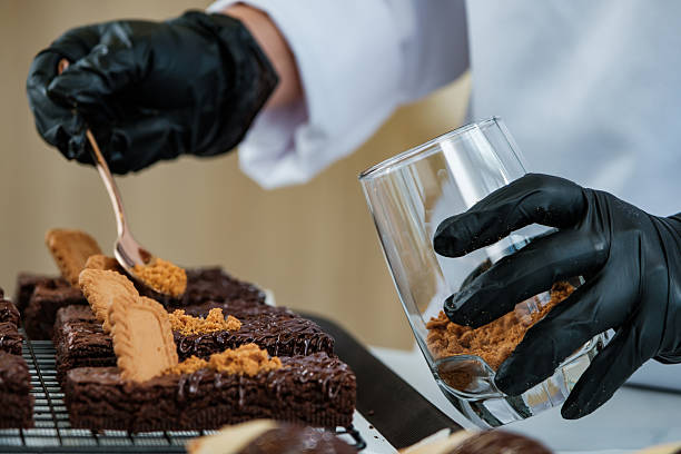 hands of chef do decorating chocolate brownie with biscuit and powder in cafe