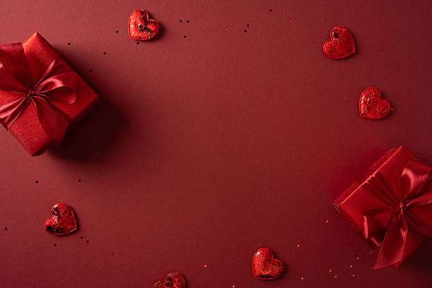 Romantic scene with red gift boxes and heart shapes scattered on a rich red backdrop, perfect for love, gifts, and Valentine celebration themes