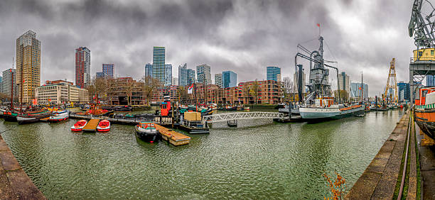 Rotterdam's Maritime museum Harbor features a mix of modern buildings, colorful boats, and a cloudy sky, showcasing the vibrant urban landscape and waterfront.