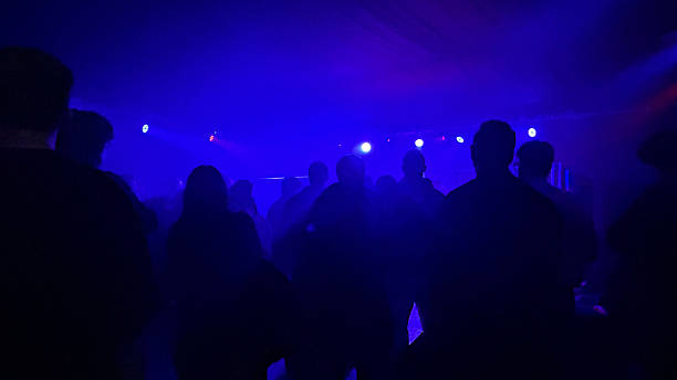 A concert audience seen from behind in soft blue light.  The people appear like shadows, creating an intense and immersive music atmosphere