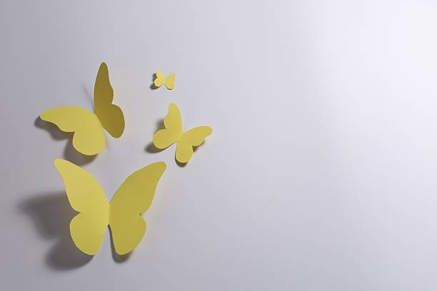 Yellow paper butterflies on light background, top view. Space for text