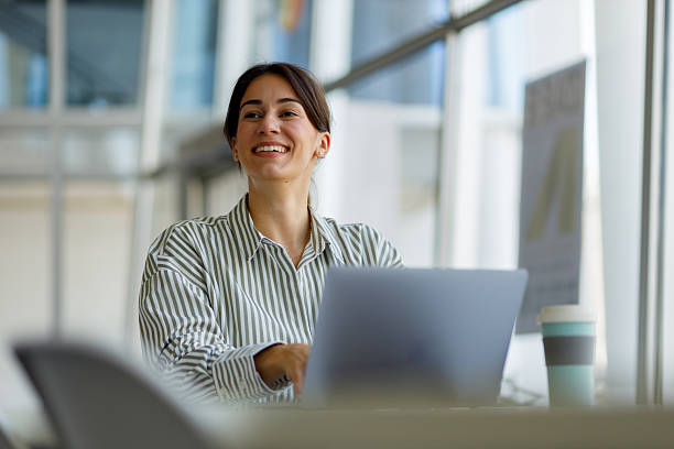 istock Woman smiling and using laptop experiencing success in a modern office, enjoying remote work and professional freedom 2255091540