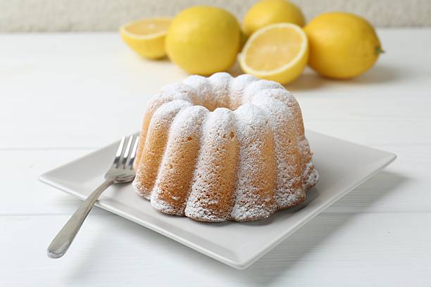 Delicious lemon cake with powdered sugar and fork on white wooden table, closeup
