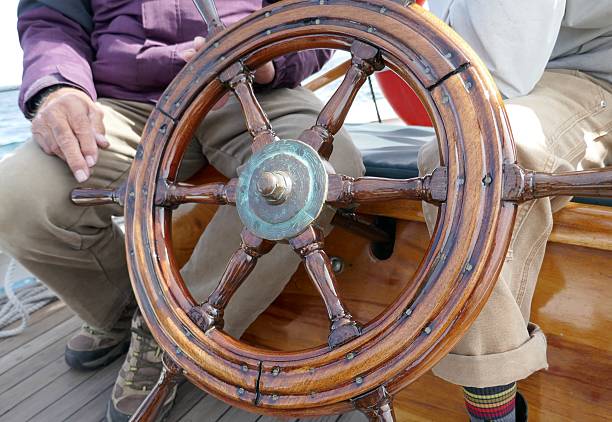 istock Ship helm or steering wheel with unrecognizable boat captain sitting down 2255094063