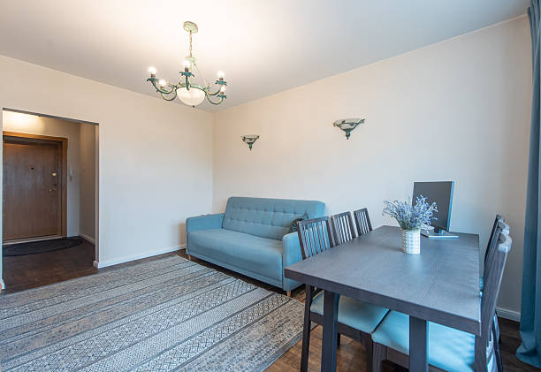 Bright and inviting living room setup featuring a comfortable sofa, dining table with chairs, stylish chandelier, and a complementing wall painting enhancing the room's ambiance.