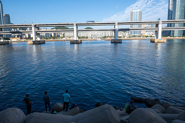 Busan, Korea - September 18, 2019: People fish near Millaksubyeon-ro, the Gwangan Bridge in the background.