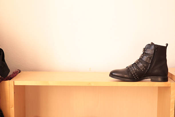 Black leather boot on wooden shelf