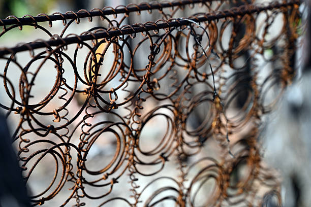 An artistic close-up of rusted bed springs uses shallow depth of field to isolate texture and form. The repeating coils create visual rhythm while conveying age and material fatigue. Ideal for abstract, industrial, and conceptual imagery.