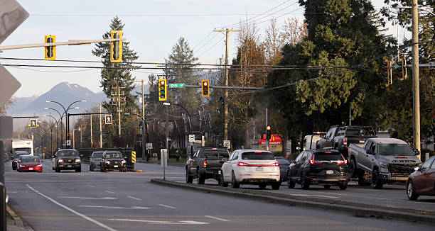 Surrey, Canada - December 31, 2025: Looking north from a TransLink bus stop on the 9500-block of 160th Street. Vehicles in line at the red stoplight in the Fleetwood-Tynehead neighourhood. Part of the British Columbia Coast Mountain Range stands in the background. Winter morning in Metro Vancouver.