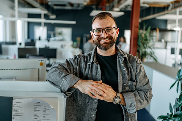 Cheerful casually clothed businessman posing for camera at modern office