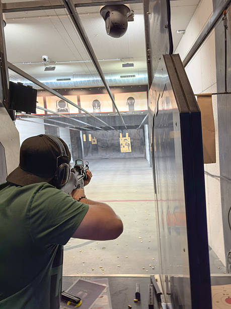 istock A person aiming a rifle inside an indoor shooting range, focused on targets downrange. 2255108117