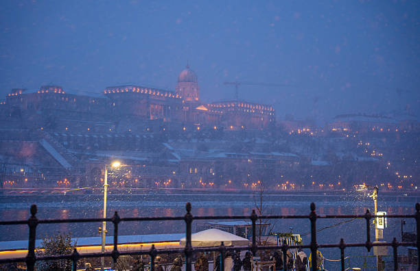 Budapest, Hungary - January 6, 2026: Buda Castle stands majestically on a hill overlooking the Danube River in Budapest, its grand facade illuminated against the heavy blue snowfall of a winter night.