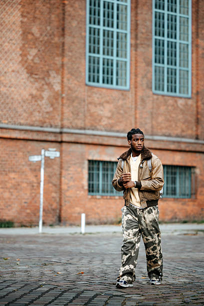 A young man walks through an urban area, observing the city around him while enjoying a leisurely exploration.
