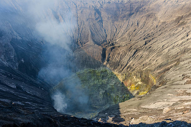 Dramatic view into the smoking crater of Mount Bromo volcano, revealing bright yellow sulfur and thick volcanic fumes rising into the air. One of Indonesia’s most iconic volcanic landscapes, located in East Java.