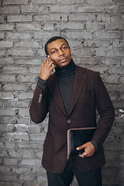 istock Young black businessman holding tablet against brick wall 2255117782