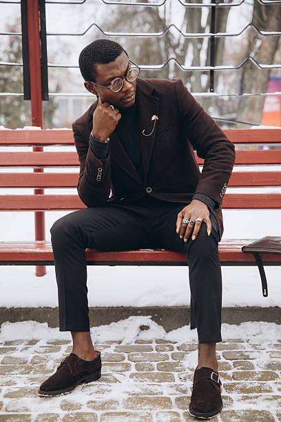 istock African man sitting on bench thinking outside in winter 2255117846