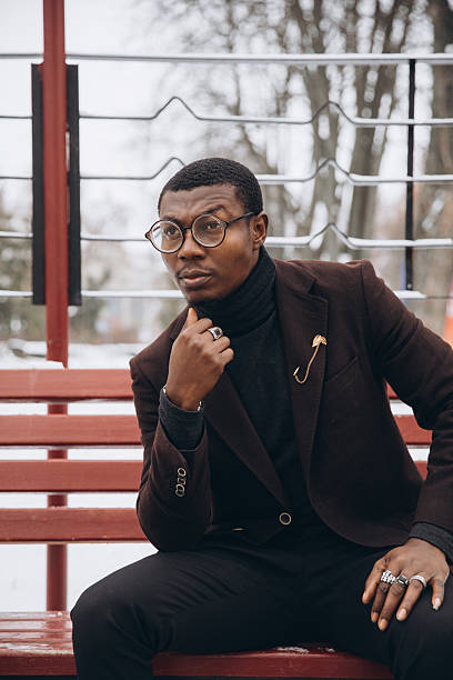 istock Young man in glasses sitting on red bench thinking 2255117848
