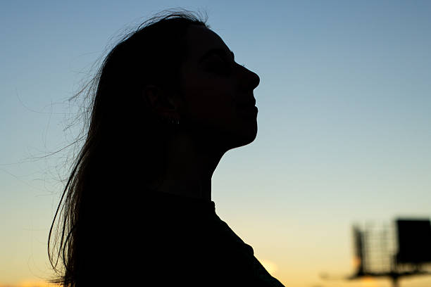 istock Young woman silhouetted against twilight sky feeling freedom 2255121321